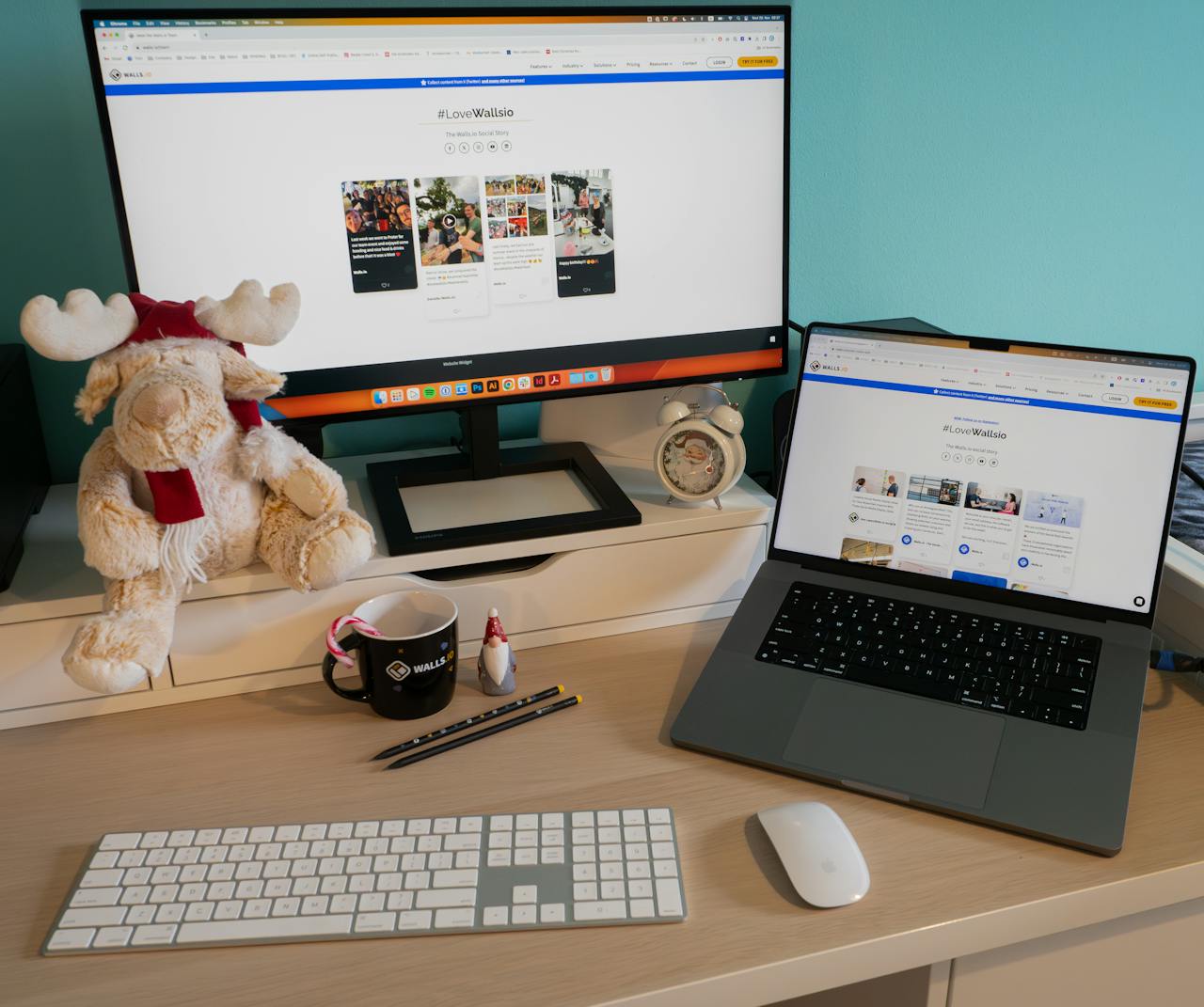 Cozy home office setup with a laptop, monitor, and teddy bear for a festive touch.